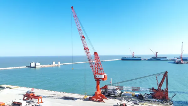 Crane portal bekerja di atas air di dermaga dengan kait terangkat