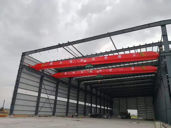 Dua overhead crane dinding tunggal dengan hoist listrik, terpasang pada rel di bengkel rangka baja baru
